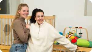 twee pedagogisch medewerkers poseren in een kinderdagverblijf van Akros kinderopvang
