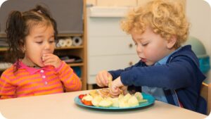 twee kinderen eten fruit op de voorschool van Akros